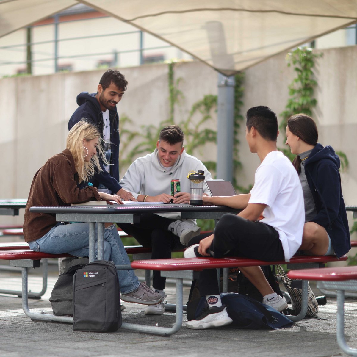 Workshop für Studierende Studierende sitzen an einem Metalltisch im Freien