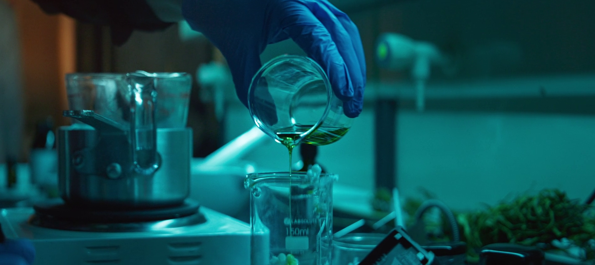 Forschungsschwerpunkt Hand mit Glas, dass eine gelbe Flüssigkeit in ein größeres Glas kippt