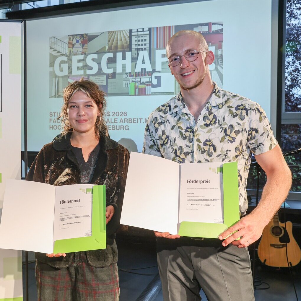 Charlotte Klein wurde für die beste Bachelorarbeit ausgezeichnet. Kalwin Kahlo erhielt die Auszeichnung für die beste Masterarbeit. 2 Personen stehen nebeneinander und freuen sich.