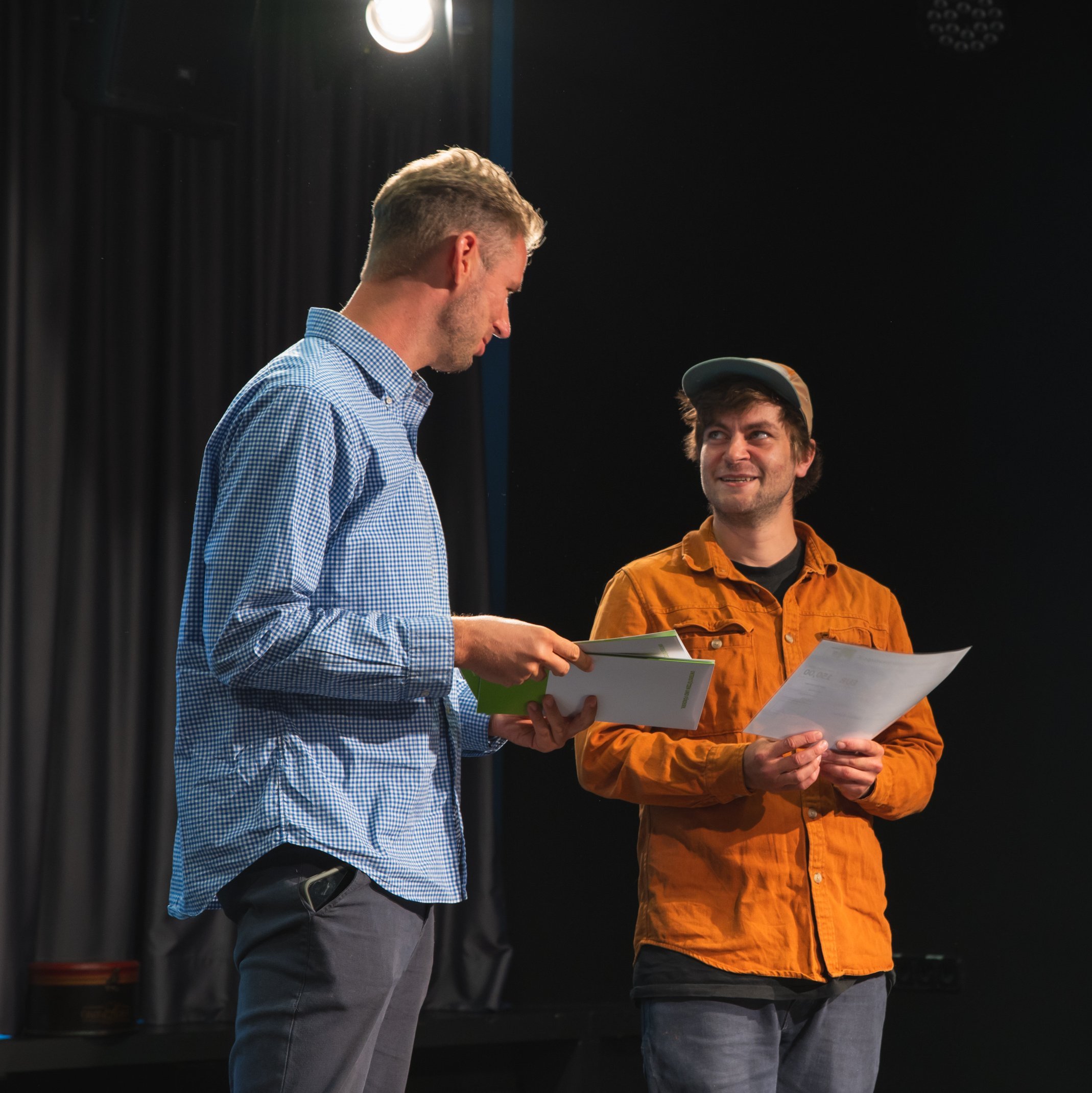 Studienabschluss SMK 2 Personen in einem dunklem Raum mit Zeugnisübergabe